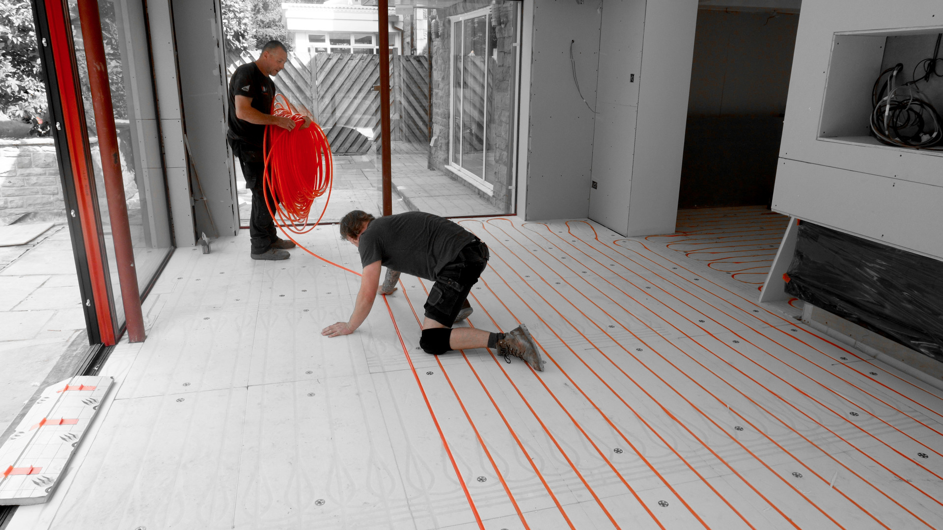BHE engineers laying flexible plastic pipes in a loop across the floor on top of insulation boards